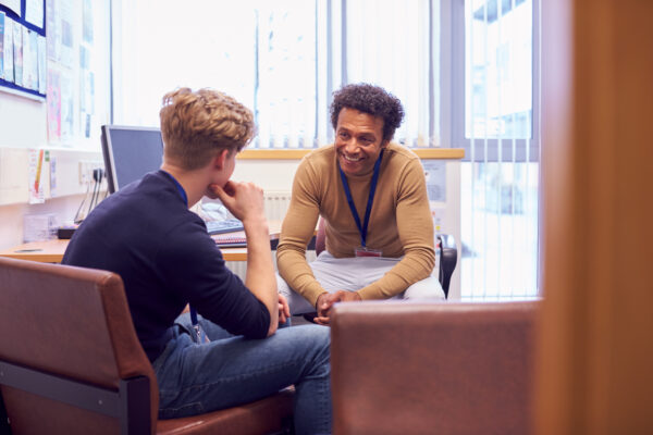 Young man sat in assessment office talking with friendly assessor