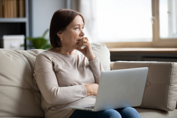 Woman with laptop on knee looking out the window