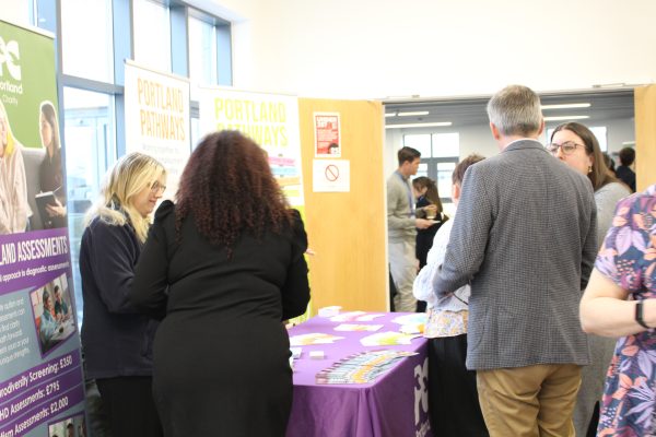 a group of men and women conversing around a promotional table.