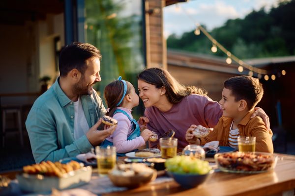 Happy family, mum, dad, daughter and son smiling while eating food at a restaurant
